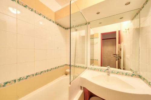 une salle de bain avec une baignoire, un lavabo et un miroir dans l'établissement Résidence La Marelle et Le Rami - maeva Home - Appartement 2 pièces 5 personnes - Sélection MAE-8644, à La Plagne Tarentaise