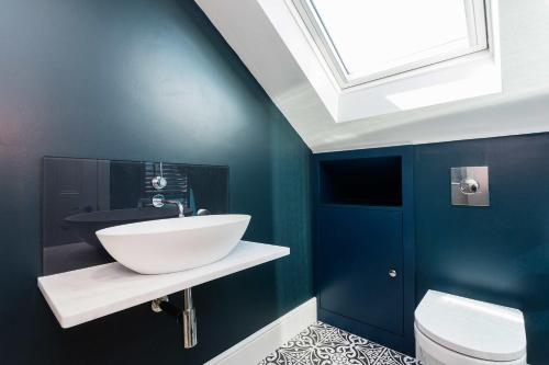 a bathroom with a white sink and a blue wall at Veeve - By Richmond Lock in Isleworth