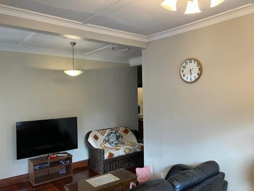 a living room with a couch and a clock on the wall at Wellington single bedroom in Wellington