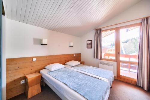 une chambre avec un lit et une grande fenêtre dans l'établissement Résidence La Marelle et Le Rami - maeva Home - Appartement 2 pièces 4 personnes - Sélection MAE-8624, à La Plagne Tarentaise