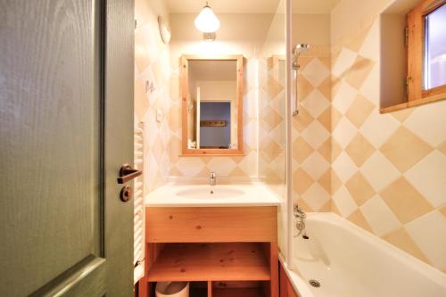 y baño con lavabo, bañera y espejo. en Résidence La Marelle et Le Rami - maeva Home - Appartement 2 pièces 4 pers 624 en La Plagne Tarentaise