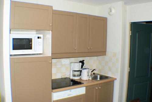 een kleine keuken met een magnetron en een wastafel bij Résidence La Marelle et Le Rami - maeva Home - Appartement 3 pièces 7 pers 654 in La Plagne Tarentaise