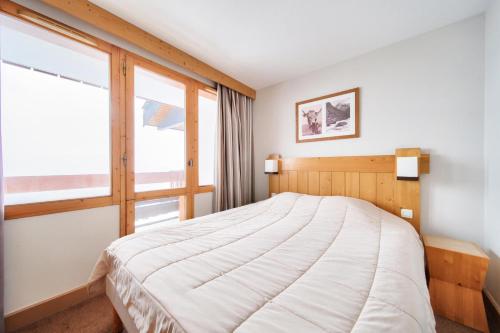 une chambre avec un grand lit et une fenêtre dans l'établissement Résidence La Marelle et Le Rami - maeva Home - Appartement 3 pièces 7 personnes - Sélection MAE-6844, à La Plagne Tarentaise