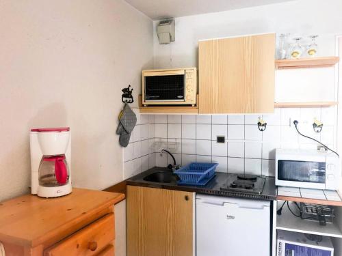 a small kitchen with a microwave and a counter top at Résidence Andromede - Studio pour 4 Personnes 384 in Vénosc