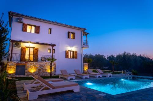 a villa with a swimming pool at night at Kostis Orange Resort in Volos
