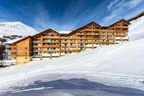 un grand bâtiment en bois dans la neige avec un tas de neige dans l'établissement Appartement 2 Pièces 4/6 Personnes MAE-4104, à La Foux