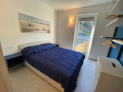 a bedroom with a bed with a blue comforter and a window at Luxury Blue Paradise Alassio in Alassio