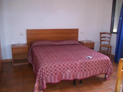 a bedroom with a bed with a red blanket on it at Agriturismo Lu Palu in Perfugas