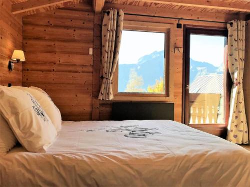 a bedroom with a bed and two windows in a cabin at Chalet Gaspard - Chalets pour 16 Personnes 494 in Vénosc