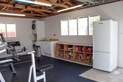 a room with a gym with a refrigerator and a treadmill at Central Villa Oasis in Whangarei