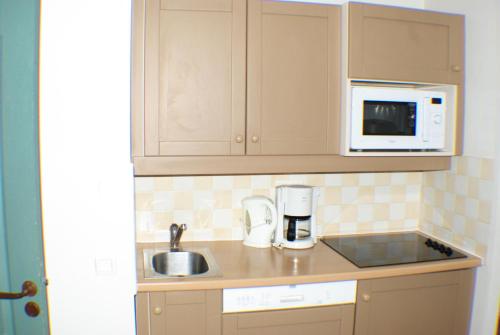 une petite cuisine avec un évier et un micro-ondes dans l'établissement Résidence La Marelle et Le Rami - maeva Home - Appartement 2 pièces 5 personnes - Sélection MAE-4514, à La Plagne Tarentaise