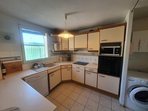 Elle comprend une petite cuisine avec des appareils électroménagers blancs et une fenêtre. dans l'établissement Face à la plage de sable, climatisation, internet, 3 chambres, à Saint-Mandrier-sur-Mer