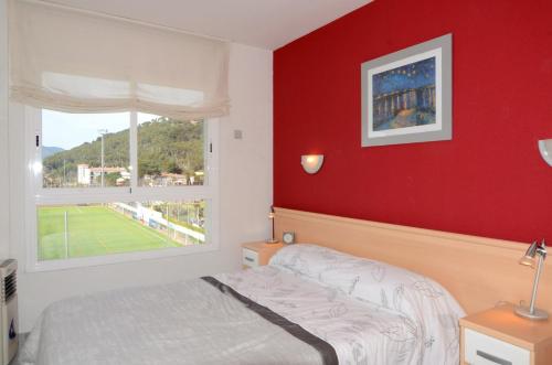 een slaapkamer met een bed en een rode muur bij Apartamento ILLA MAR DOR 335 in L'Estartit