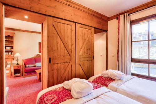 two beds in a room with a wooden door at Résidence Les Arcs Le Village - maeva Home - Appartement pièces - Prestige 134 in Bourg-Saint-Maurice