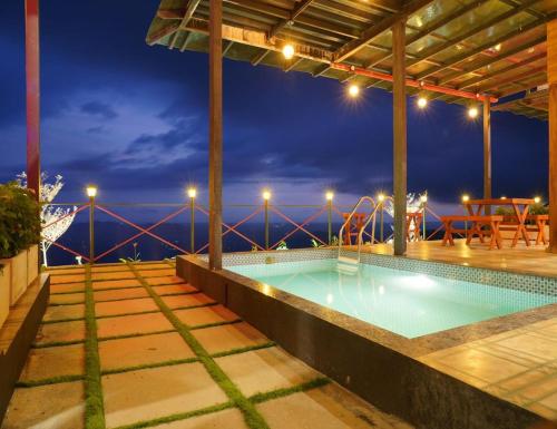 a swimming pool with a view of the ocean at night at Vayalada View Point Resort in Kozhikode