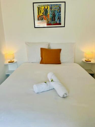 - une serviette roulée sur un lit blanc avec deux lampes dans l'établissement ''Ophélia 22'' Joli T2 avec clim et parking, à Sète