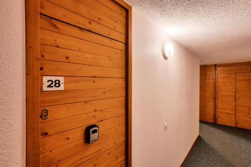 un couloir doté d'un mur en bois avec un numéro. dans l'établissement Quartier La Forêt - maeva Home - Studio 4 personnes - Sélection MAE-7384, à Valmorel