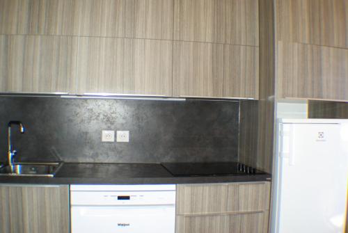 Il comprend une cuisine équipée d'un comptoir noir et d'un réfrigérateur. dans l'établissement Résidence Le Hameau du Sauget - maeva Home - Appartement duplex 2 pièces 4 personnes - Sélection MAE-2604, à La Plagne Tarentaise