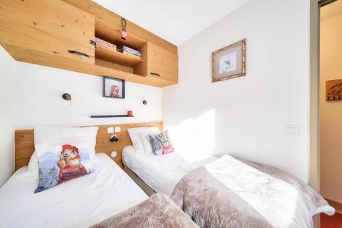 deux lits dans une chambre aux murs blancs dans l'établissement Résidence La Marelle et Le Rami - maeva Home - Appartement 2 pièces 4 personnes - Sélection MAE-0944, à La Plagne Tarentaise