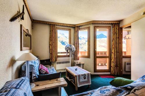 - un salon avec un canapé, une table et des fenêtres dans l'établissement Résidence Callisto - maeva Home - Appartement 3 pièces 6 personnes - Budget MAE-8964, à Aime La Plagne