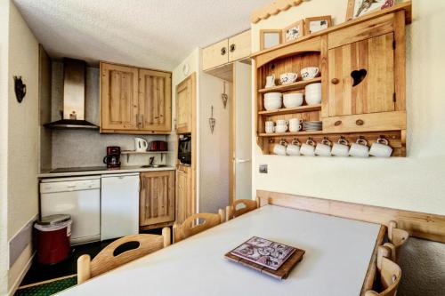 Il comprend une cuisine équipée d'une table blanche et d'un réfrigérateur blanc. dans l'établissement Résidence Callisto - maeva Home - Appartement 3 pièces 6 personnes - Budget MAE-8964, à Aime La Plagne