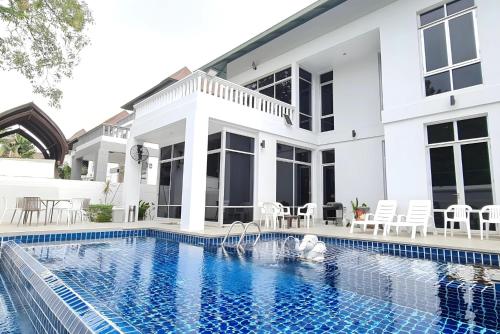 a house with a swimming pool in front of it at BM Pool Villa Pattaya in Na Jomtien
