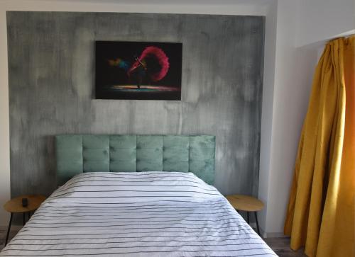 a bedroom with a bed and a painting on the wall at Mall Apartment 100mp in Bacău