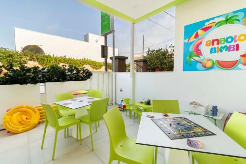 un restaurante con mesas blancas y sillas verdes en Marini Hotel B&B, en Lido Marini