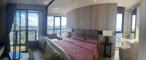 a bedroom with a large bed with a large window at THE PANORA PATTAYA in Pattaya South