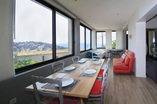 une salle à manger avec une grande table, des chaises et des fenêtres dans l'établissement Vue mer, contemporain, climatisation, jardin, Terrasse, 2 Salles de bains, à Saint-Mandrier-sur-Mer