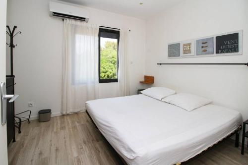 une chambre avec un lit blanc et une fenêtre dans l'établissement Vue mer, contemporain, climatisation, jardin, Terrasse, 2 Salles de bains, à Saint-Mandrier-sur-Mer