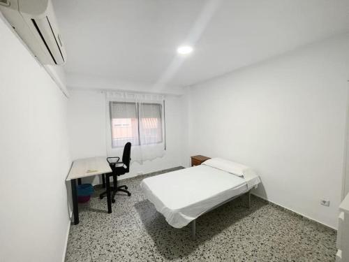 a small white room with a bed and a desk at Piso completo en Calle Rafael in San Vicente del Raspeig