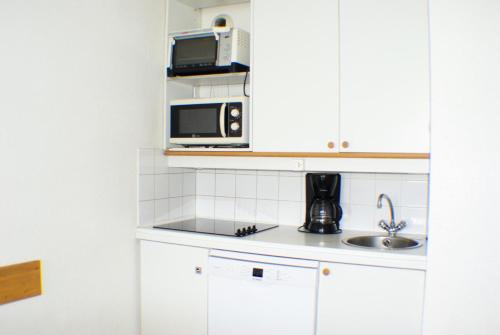 une petite cuisine avec un micro-ondes et un évier dans l'établissement Résidence Le Hameau du Sauget - maeva Home - Appartement 4 pièces 7 personnes - Sélection MAE-4354, à La Plagne Tarentaise