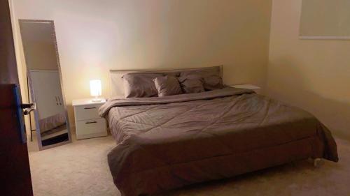 1 dormitorio con 1 cama y mesita de noche con lámpara en شقة بغرفه نوم وصالة, en Az Zulfi