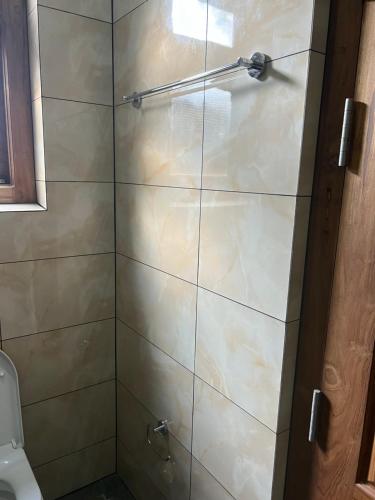 ducha con puerta de cristal y aseo en DOCKYARD HOTEL en Trincomalee