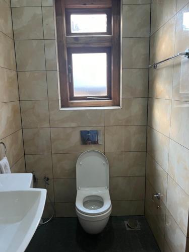 a bathroom with a toilet and a sink and a window at DOCKYARD HOTEL in Trincomalee