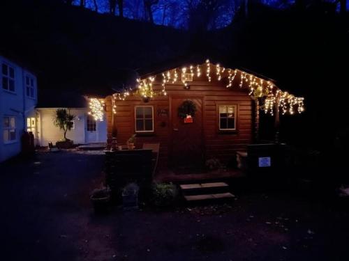 a house with christmas lights on it at night at Panteinion Hall- The Cabin in Fairbourne