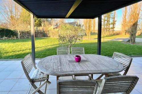 einen Holztisch mit Stühlen und eine rosa Tasse drauf in der Unterkunft La Prestigieuse - MALO’Cation in Leffrinckoucke