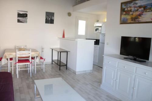 een keuken en eetkamer met een tafel en een televisie bij Appartement 1809 Tennis village 6 personnes in Cap d'Agde