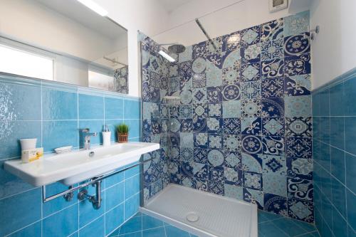 La salle de bains est pourvue de carrelage bleu, d'un lavabo et d'une douche. dans l'établissement Casa Luna Sul Mare, à Praiano