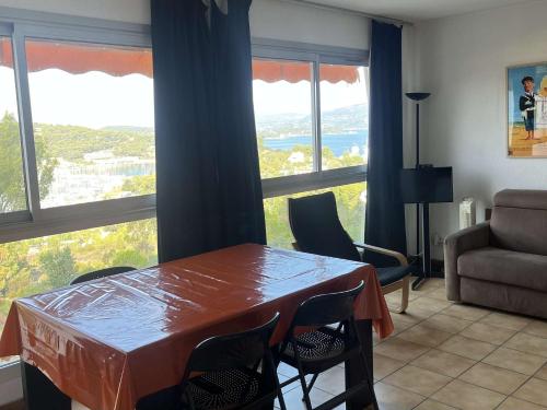 un salon avec une table, des chaises et des fenêtres dans l'établissement Vue mer, WIFI, coeur du village, piscine, tennis ...Tout à pied, à Saint-Mandrier-sur-Mer