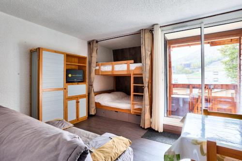 Schlafzimmer mit Etagenbetten und Balkon in der Unterkunft Résidence Le Hameau - maeva Home - Studio 4 personnes - Sélection 854 in Vars