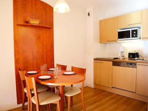 eine Küche mit einem Holztisch und Stühlen sowie eine Küche mit einem Tisch in der Unterkunft Résidence Pic Du Midi - 2 Pièces pour 4 Personnes 264 in La Mongie