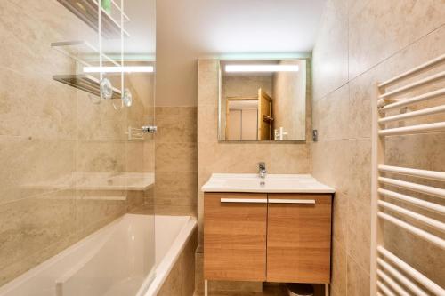 une salle de bain avec un lavabo, une baignoire et un miroir dans l'établissement Résidence Le Chalet des Rennes - maeva Home - Appartement 3 pièces 7 personnes - Exclusive MAE-6294, à Vars