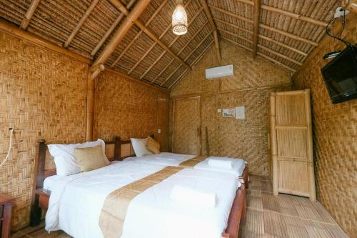 sypialnia z dużym łóżkiem w pokoju w obiekcie The Lavana Cici Bungalow Senggigi w mieście Senggigi