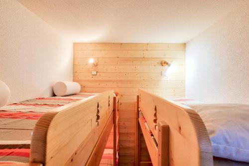 two beds in a bedroom with wooden walls at Quartier Crève Cœur - maeva Home - Appartement 2 pièces 5 personnes - Con 244 in Valmorel