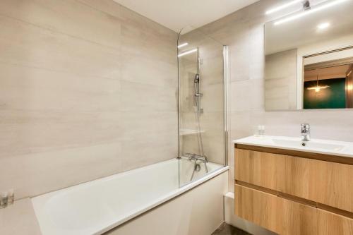 y baño con bañera, lavamanos y ducha. en Résidence Les Arcs Le Village - maeva Home - Appartement pièces - Exclusiv 761, en Arc 1950