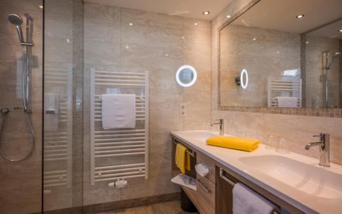a bathroom with a shower and a sink and a mirror at Hotel Bichlingerhof in Westendorf