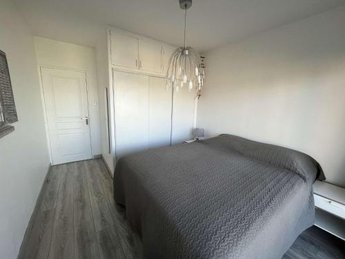 een slaapkamer met een bed en een kroonluchter bij Appartement 2 chambres, climatisation, vue mer, refait à neuf en 2020 in Saint-Mandrier-sur-Mer