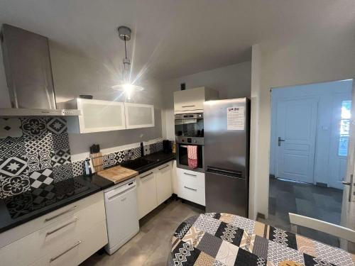 La cuisine est équipée de placards blancs et d'un réfrigérateur en acier inoxydable. dans l'établissement Appartement 2 chambres, climatisation, vue mer, refait à neuf en 2020, à Saint-Mandrier-sur-Mer